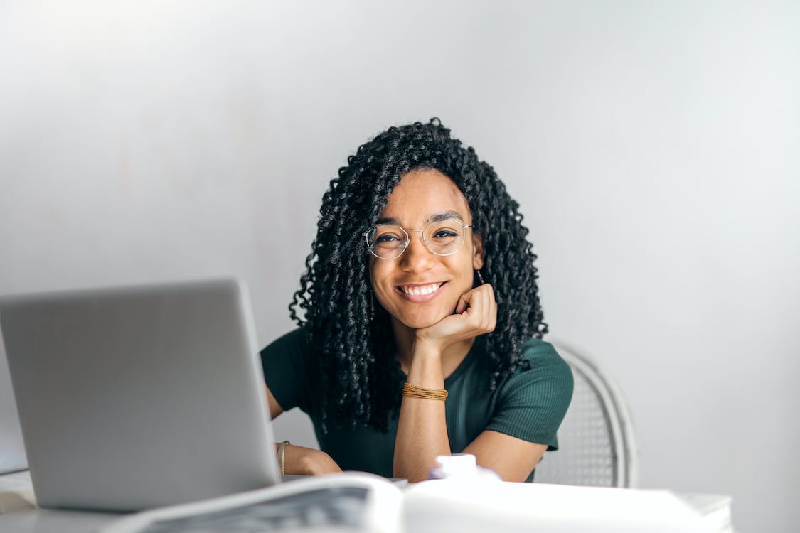 Free Happy ethnic woman sitting at table with laptop Stock Photo